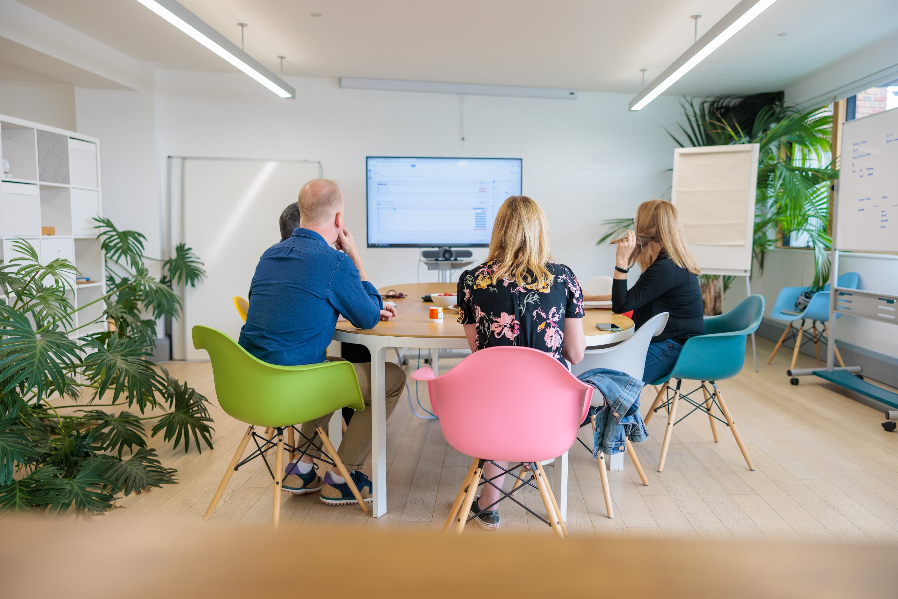 Four people sit in colourful chairs around a table at our ecommerce agency headquarters.